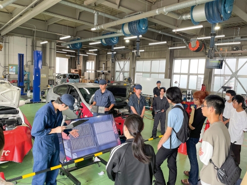 昨年度行われたオープンキャンパスの様子の写真です。自動車技術科実習場において多数の参加者が説明を受けている様子が写っています。