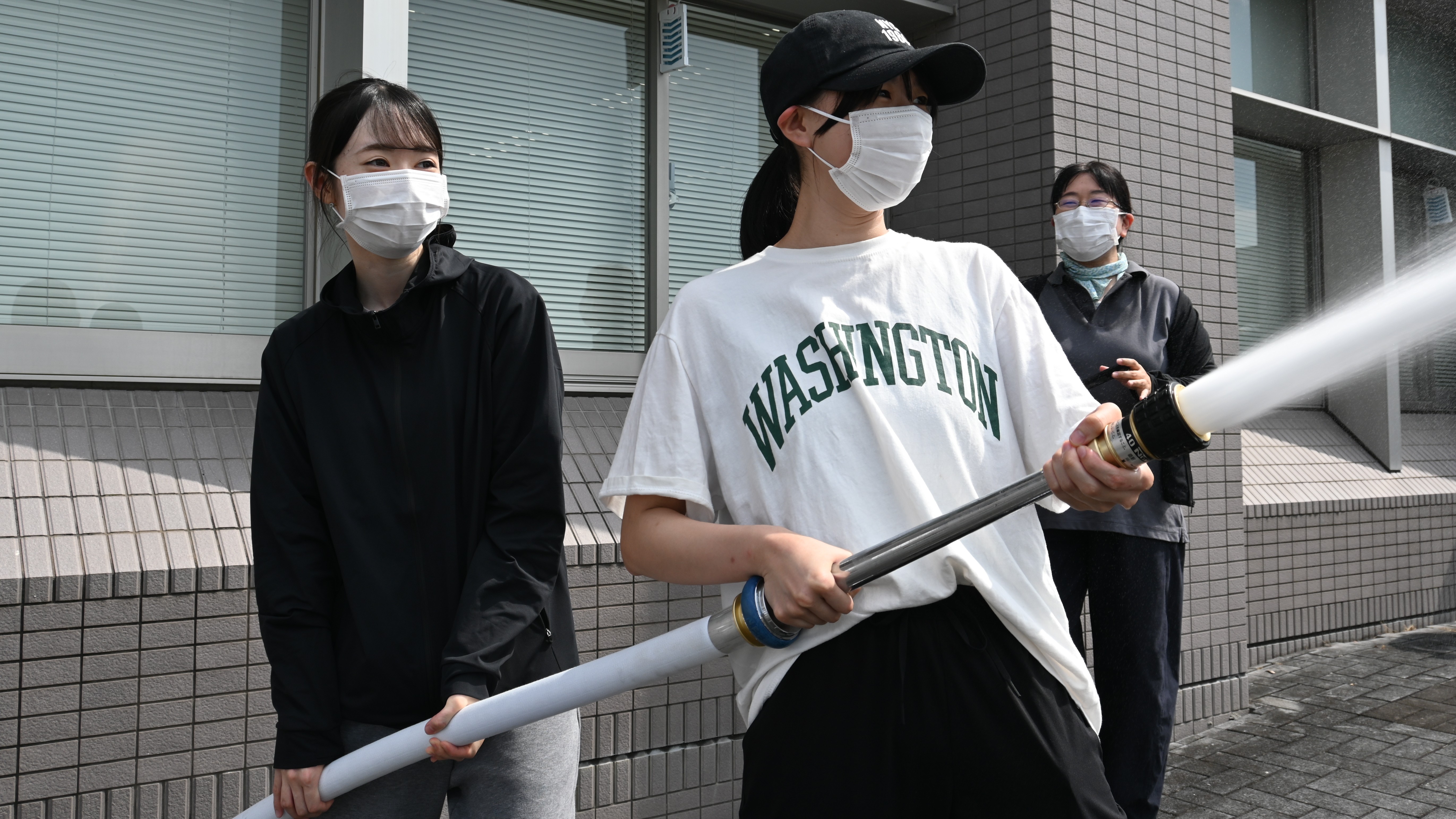 消防用ホースを使用して放水訓練に取り組む学生