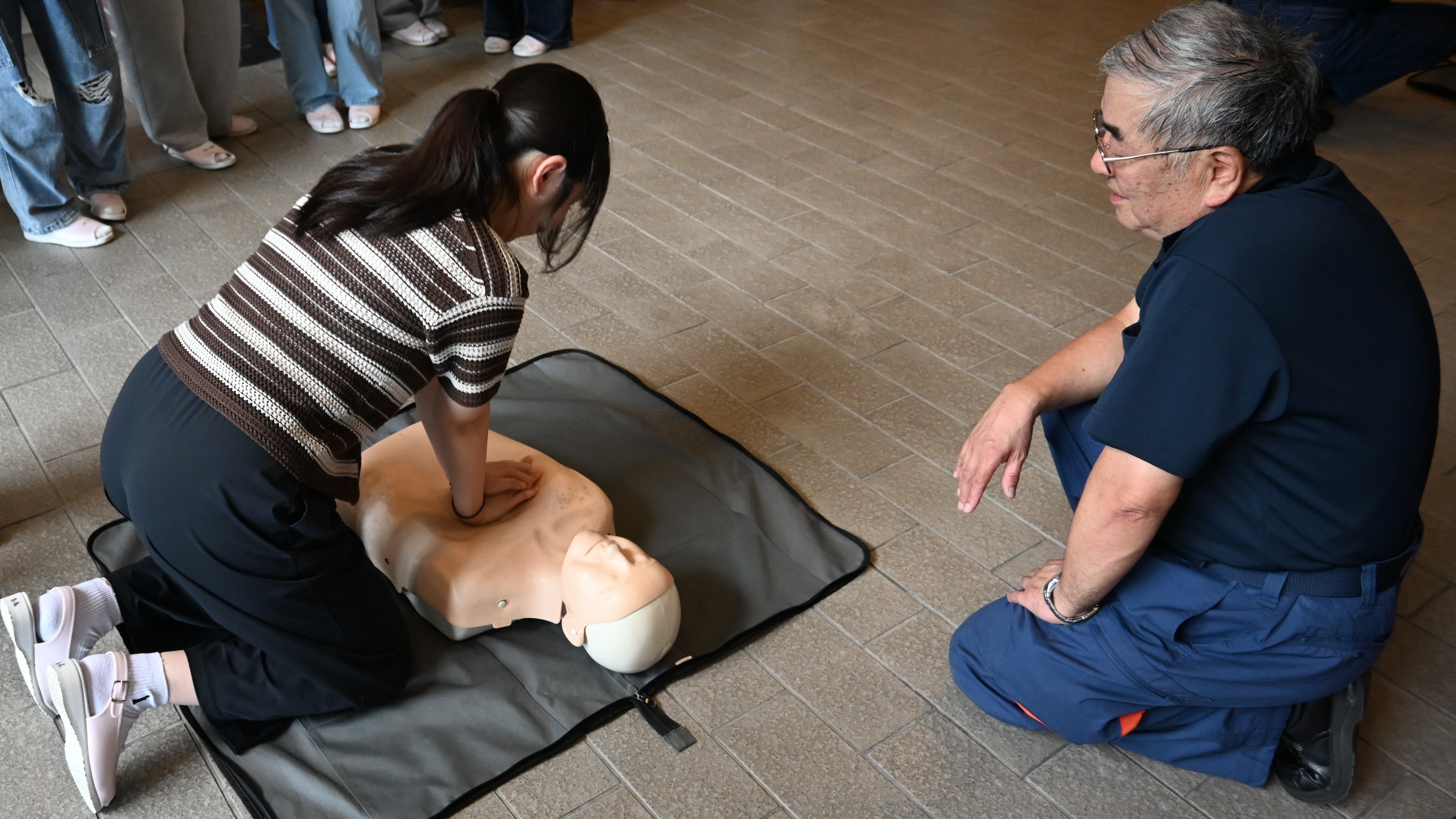 消防職員の指導を受けながら胸骨圧迫に取り組む学生