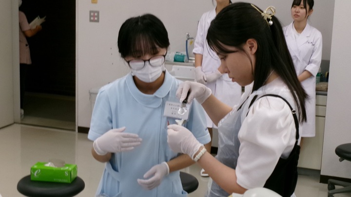 アルジネート印象材を使った印象採得について学生が参加者に説明する様子
